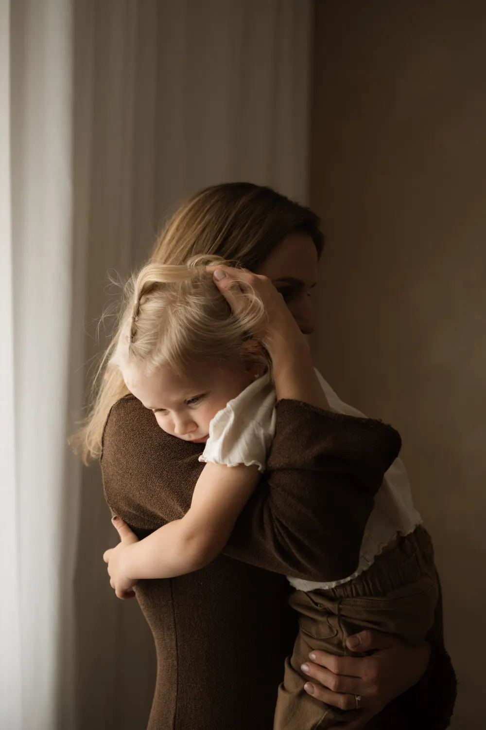 Maminka drží v náručí svou tříletou dceru během focení v ateliéru