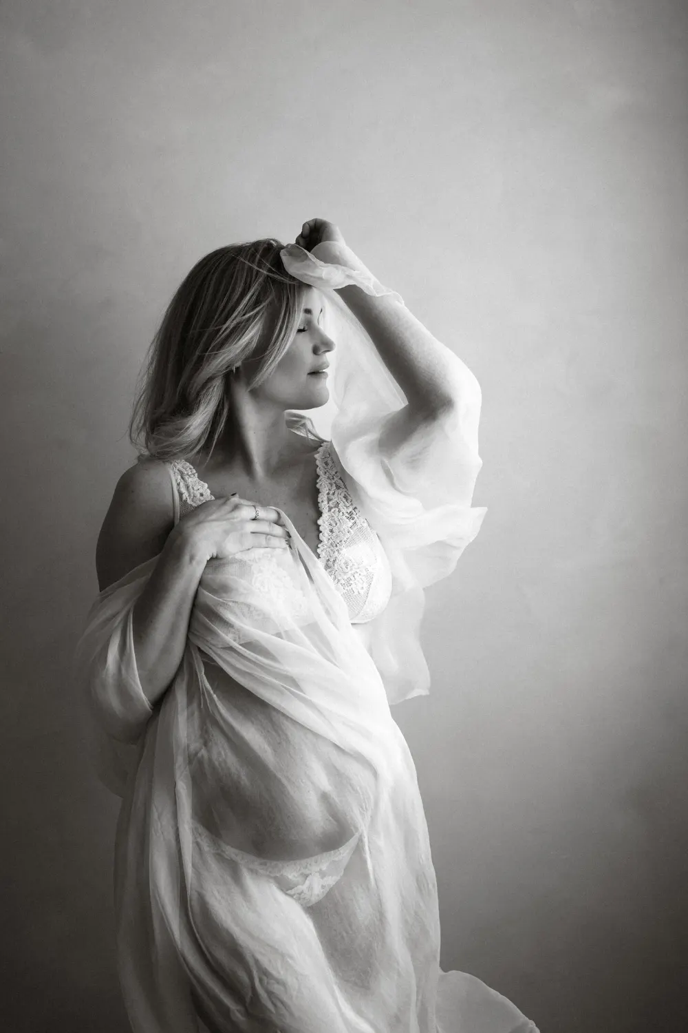 Těhotná žena pózuje v ateliéru zabalená do splývavé látky