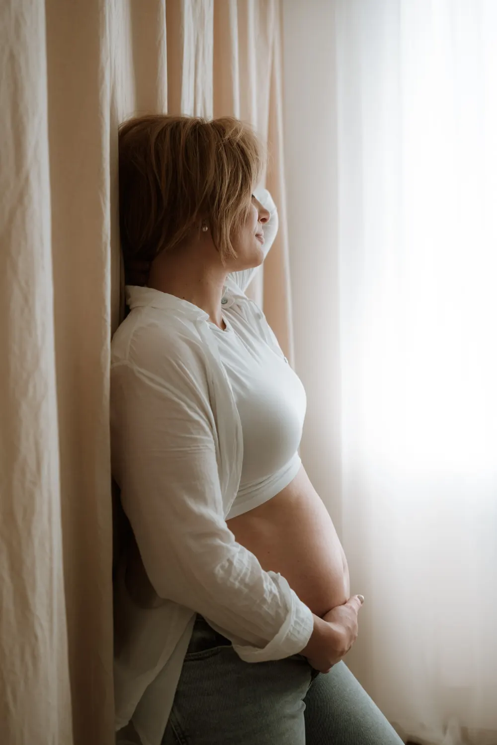těhotná žena s holým bříškem se opírá o zeď