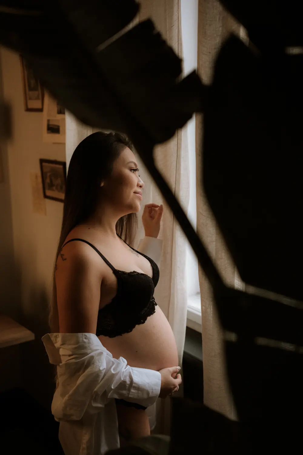 těhotná žena ve spodním prádle kouká z okna