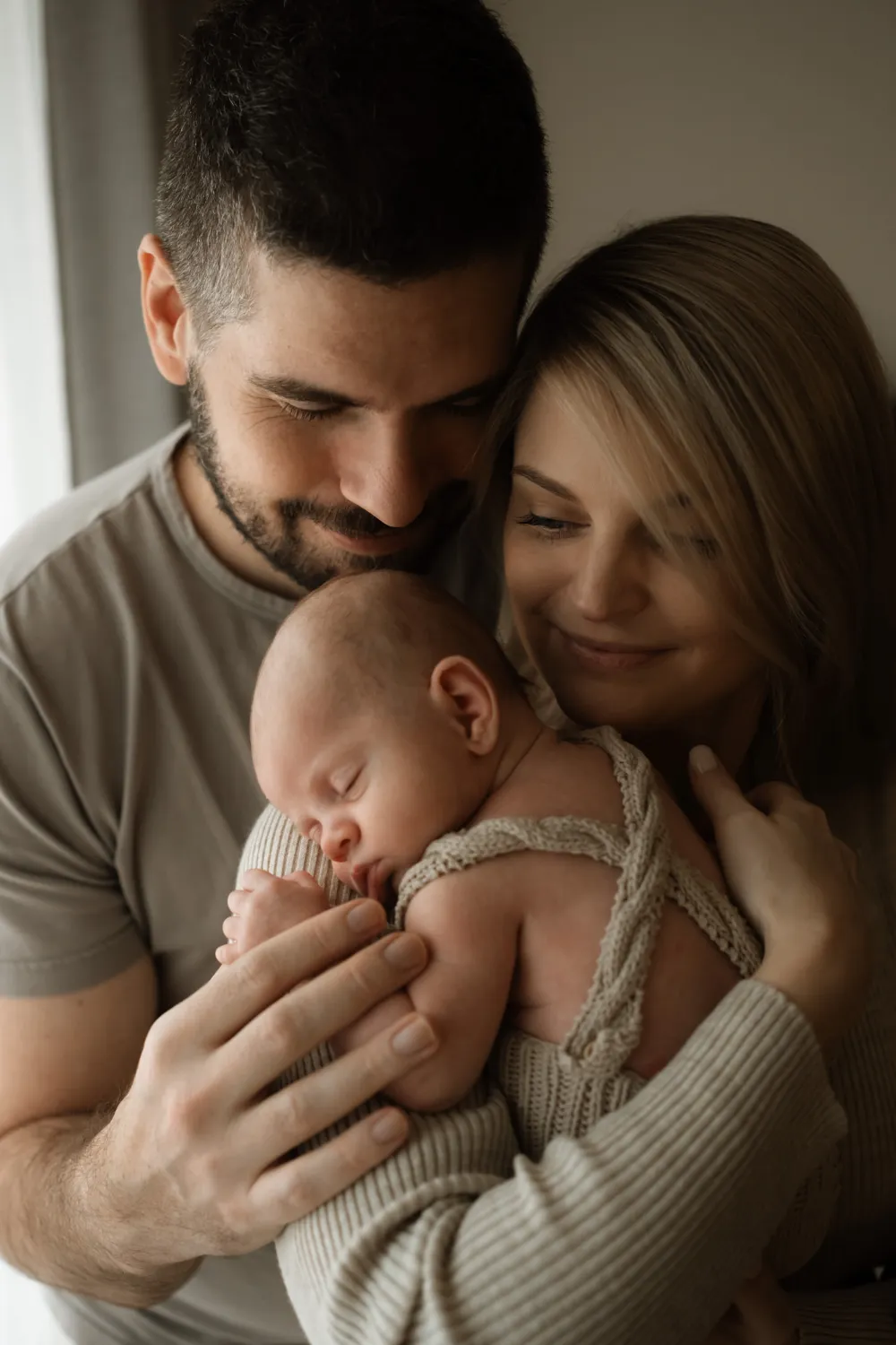 focení newborn praha - maminka chová novorozence na rameni a tatínek ho hladí po ručičce