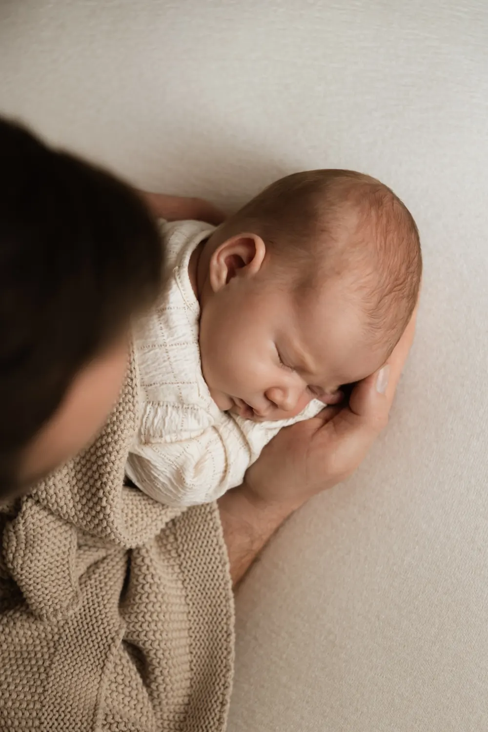 miminko spící v rukách tatínka - focení v minimalistickém ateliéru v Praze