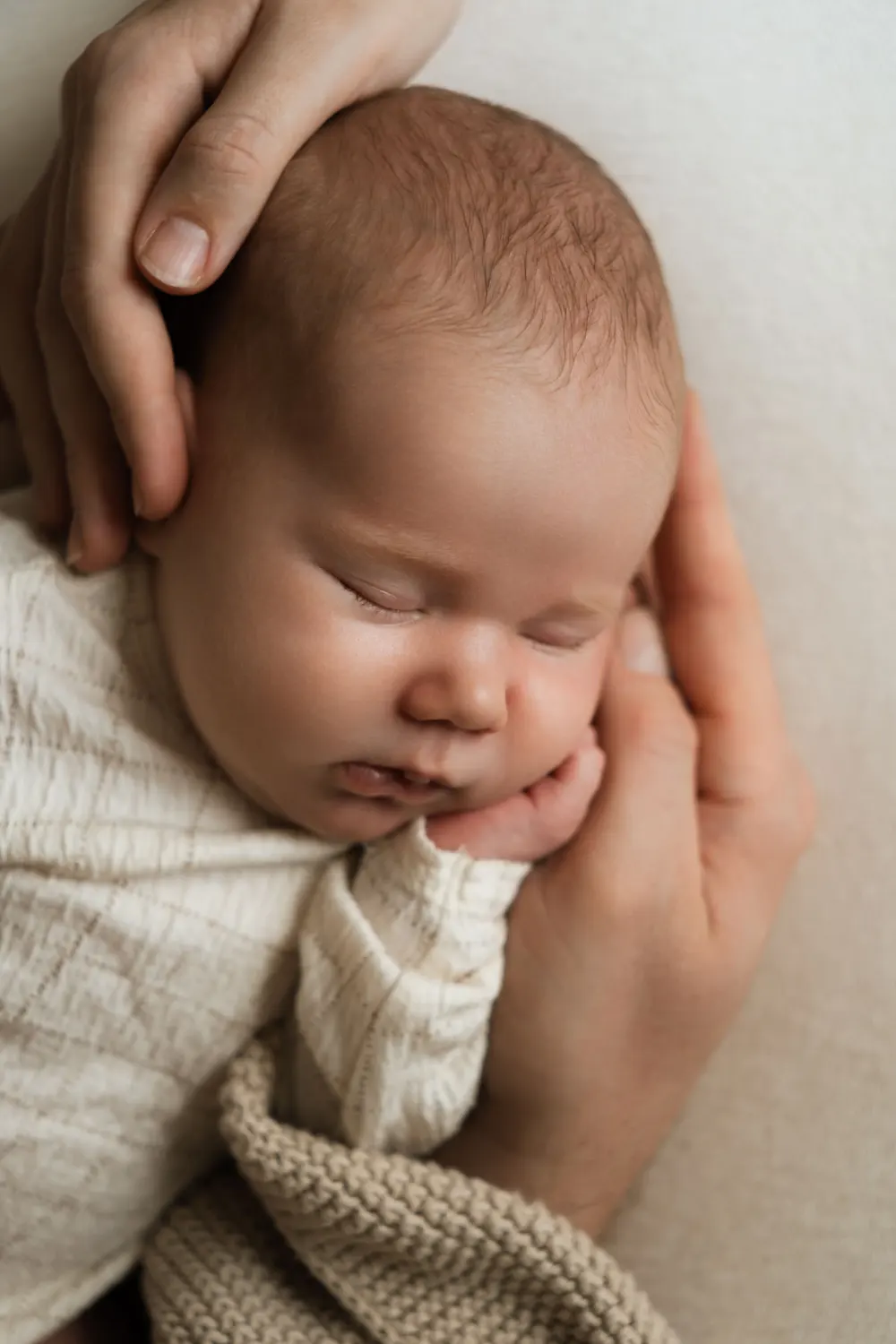 newborn focení v ateliéru - miminko spí v rukách rodičů